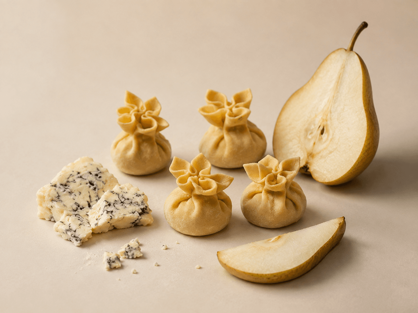 Fiocchetti Gorgonzola & Pere, their pasta gathered and pleated at the top, with cheese and pear beside them.